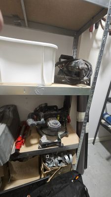 a man standing next to a shelf with tools on it