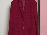 a red jacket hanging on a rack in front of a pink wall