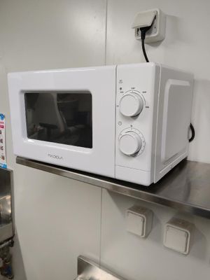 un micro-ondes blanc posé sur un plan de travail en inox