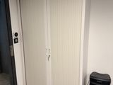 une armoire blanche avec une poubelle noire à côté