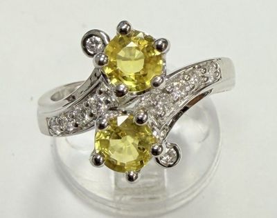 un gros plan d'une bague sertie d'un diamant jaune et blanc posée sur une surface transparente