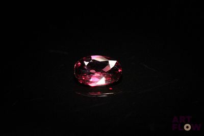 a close up of a pink gems stone on a black surface