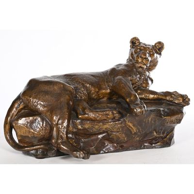 a bronze statue of a lion laying on top of a rock