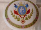 une assiette blanche ornée d'un emblème bleu et or