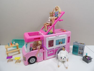 deux poupées Barbie assises sur le toit d'un petit bus rose