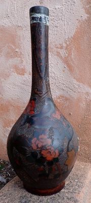 a black vase sitting on the ground next to a wall