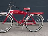 a red bike that is parked in front of a garage