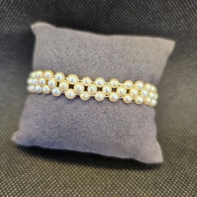 un gros plan d'un bracelet de perles blanches posé sur un oreiller