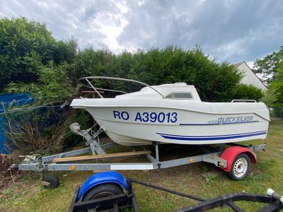 un bateau posé sur une remorque dans l'herbe