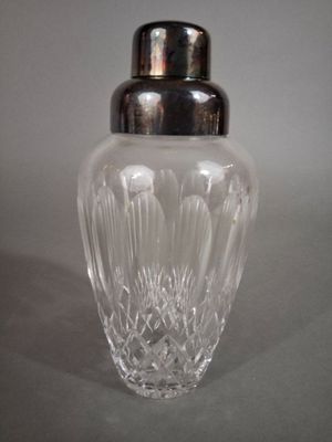 un vase en verre muni d'un couvercle en argent, posé sur une table