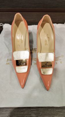 les chaussures sont posées sur un sac blanc orné d'une boucle dorée