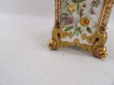 a small clock with flowers on it on a white surface