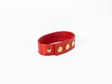 un gros plan d'un bracelet en cuir rouge posé sur une surface blanche