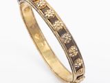 a close up of a gold and black enamel bangle
