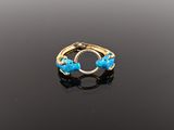 an image of a gold ring with blue stones on a black surface