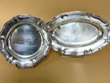 deux plateaux en argent posés l'un à côté de l'autre sur une table