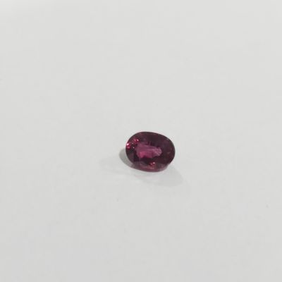 an oval shaped pink sapphire stone on a white surface