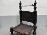 une chaise en bois avec une assise tressée, placée devant un mur blanc