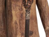 an old wooden statue of a man with a cane in his hand