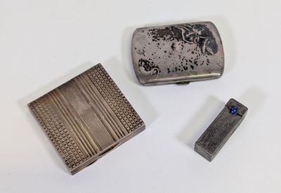 un étui à cigarettes en argent et un briquet posés sur une table blanche