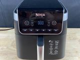 an air fryer sitting on top of a wooden table next to a black wall