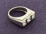 a silver ring with three diamonds on it on a purple surface