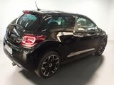 the back end of a small black car parked in a garage
