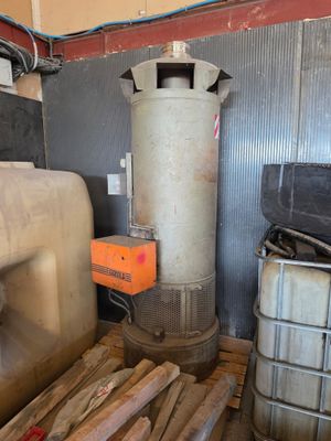 un grand réservoir métallique posé à côté d'une pile de bois