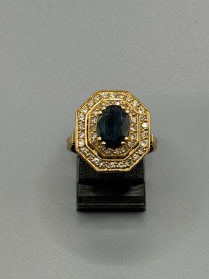 un gros plan d'une bague en or sertie d'une pierre bleue entourée de diamants blancs