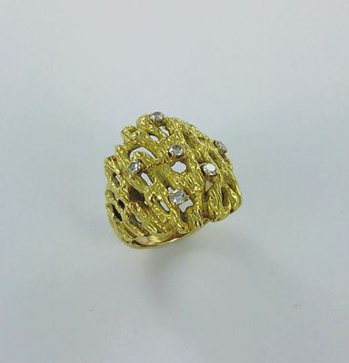 gros plan d'une bague en or avec des diamants sur une surface blanche