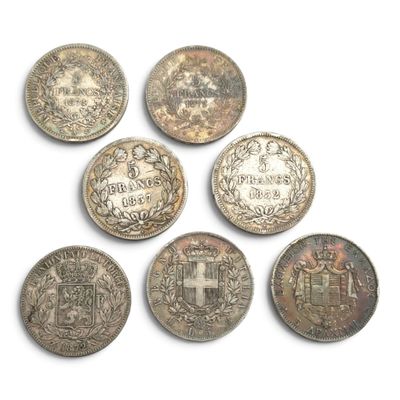 six pièces d'argent de formes et de tailles différentes sur une surface blanche