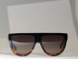 des lunettes de soleil noires et écaille posées sur une surface blanche, sur fond blanc