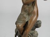 statue en bronze représentant une femme assise sur un rocher, tenant un oiseau dans ses mains