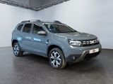 the grey dacia is parked in a large room with a white wall
