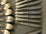 a lot of silver spoons and forks arranged on a table