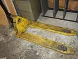 un chariot élévateur jaune posé au sol dans une pièce
