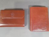 two brown leather wallets sitting next to each other on a table