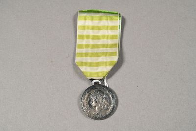 a silver medal with a green and white ribbon around it