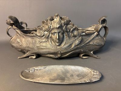 a silver plate with a face on it next to a mirror