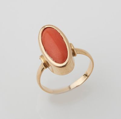 a gold ring with an oval coral stone in the center