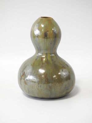un vase vert posé sur une surface blanche