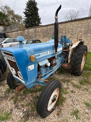 un tracteur bleu garé près d'un mur de briques