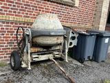 une bétonnière à côté de deux poubelles, près d'un immeuble