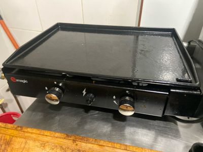 une plaque de cuisson noire posée sur une table en bois