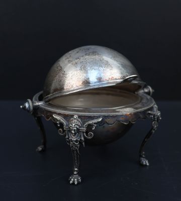un plat ancien en argent avec un couvercle bombé, posé sur un socle