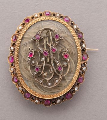an image of a gold and ruby broochle with a monogram on it