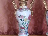 two vases sitting on a table with a pink wallpaper behind them
