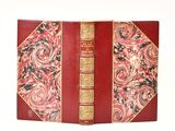 un vieux livre avec une couverture rouge et des bordures dorées sur fond blanc