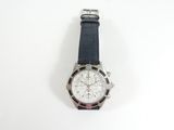 une photo d'une montre posée sur une surface blanche, avec un bracelet noir