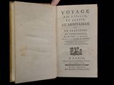 someone is holding an old book open on a black surface